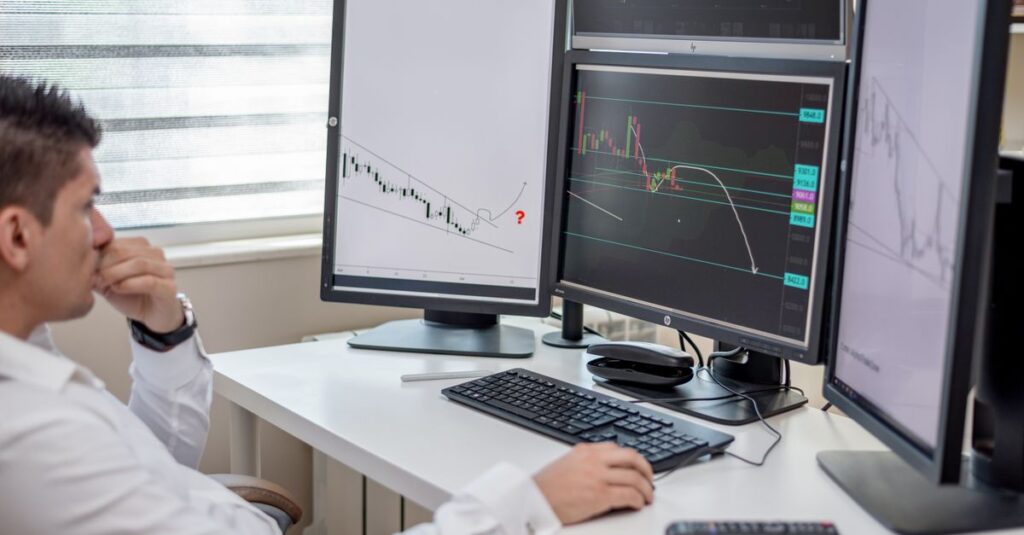 Multi-monitor trading desk displaying RSI and MACD momentum indicators below a Forex MT4 chart