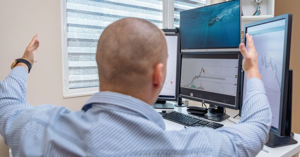 Multi-monitor MetaTrader desk running a gold scalping indicator setup on XAUUSD one minute charts