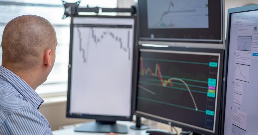 Trader at a desk installing an ATR trailing stop indicator on trading platform screens